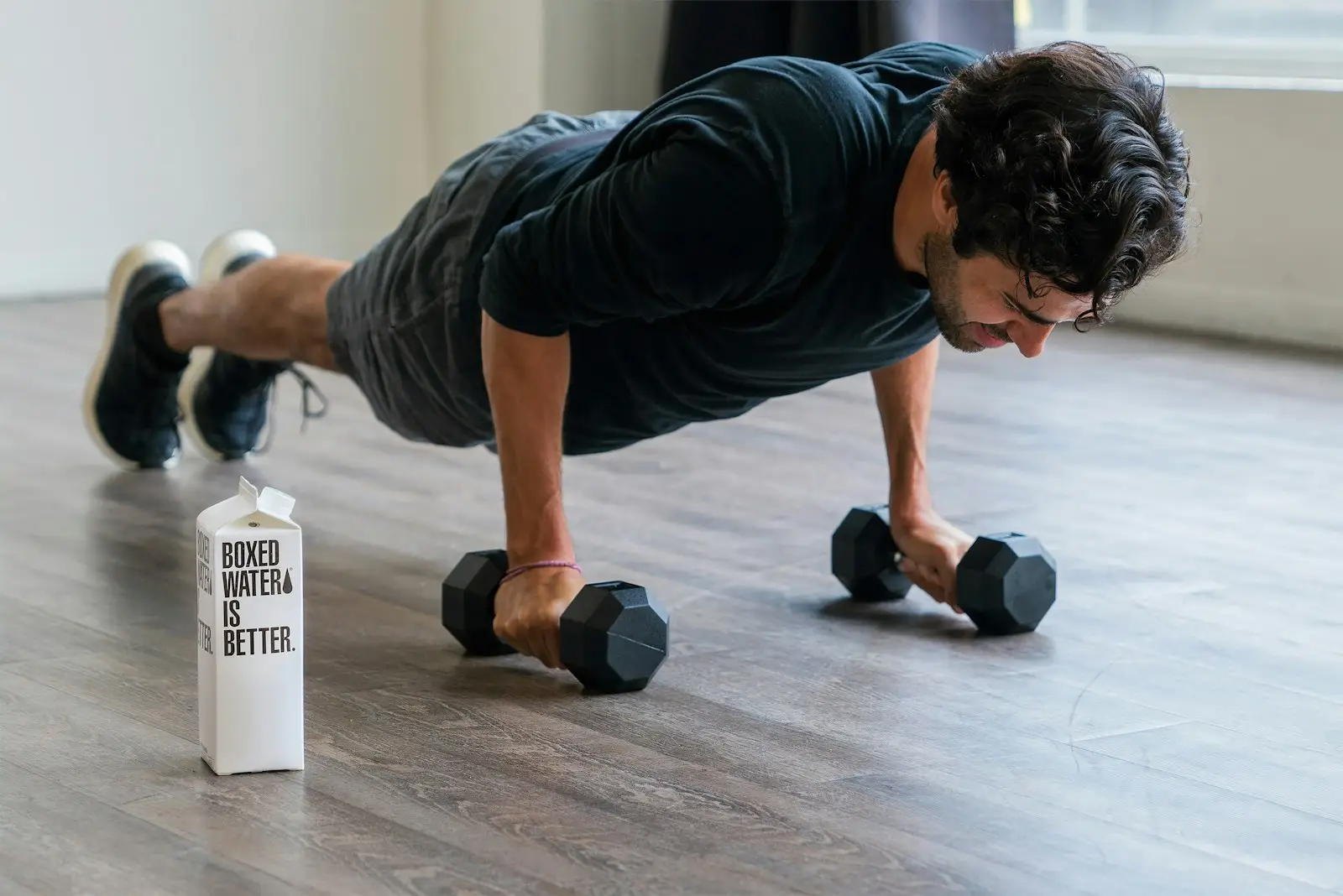 Man doing dumbbell push-ups on a living room floor